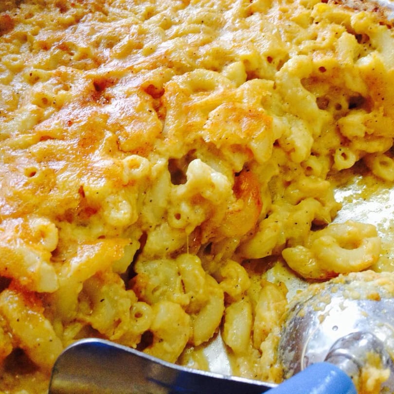 Close-up of Aunt Berta's Kitchen's baked macaroni and cheese with a serving spoon.