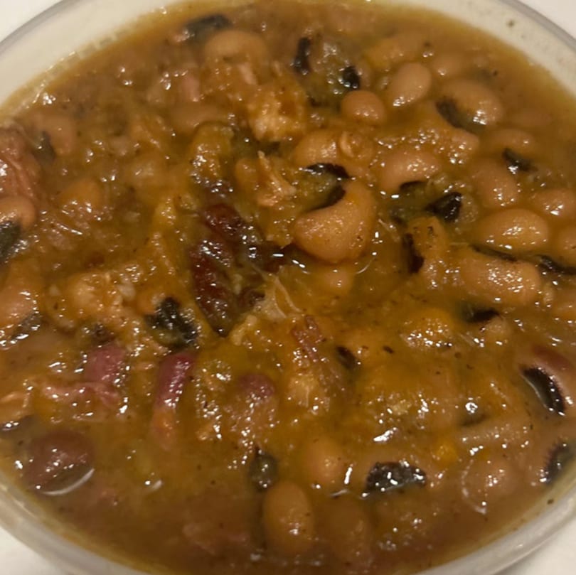 A close-up of Aunt Berta's Kitchen's soul-food black-eyed peas with ham hocks in a rich brown sauce.