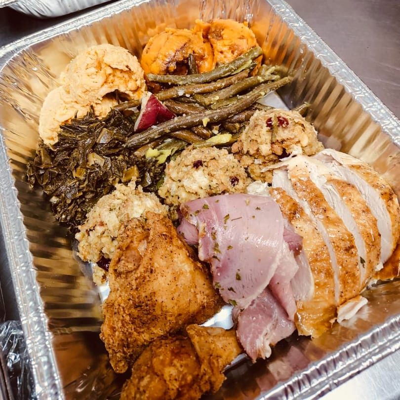 Aunt Berta's Kitchen soul food spread with fried chicken, sliced turkey, ham, collards, green beans, stuffing, and yams.